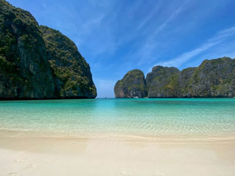 Empty Maya Bay under full sunlight, showing clear water and limestone cliffs
